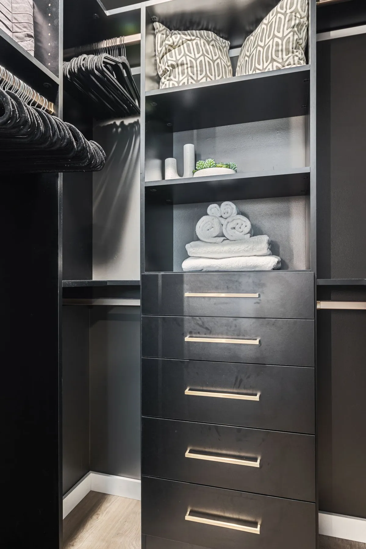 Shelves neatly stacked with patterned pillows, rolled towels, and decorative items create an organized, tidy environment. The setup suggests that all essentials are readily available and easily accessible for guests.