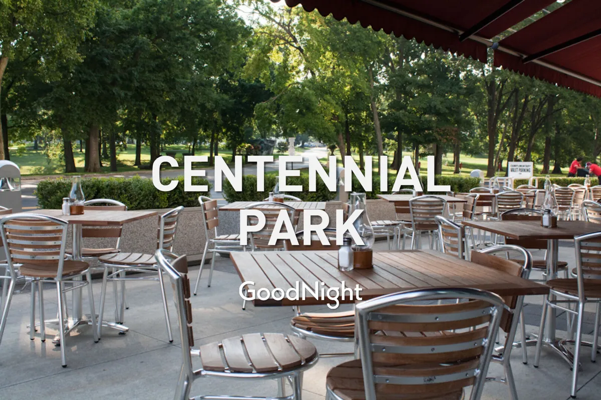 This exterior image features outdoor dining tables set beneath a canopy, surrounded by lush greenery. The scene is relaxed, with people dining and socializing as the sun sets, evoking the ambiance of Nashville's vibrant dining patios and local restaurants.